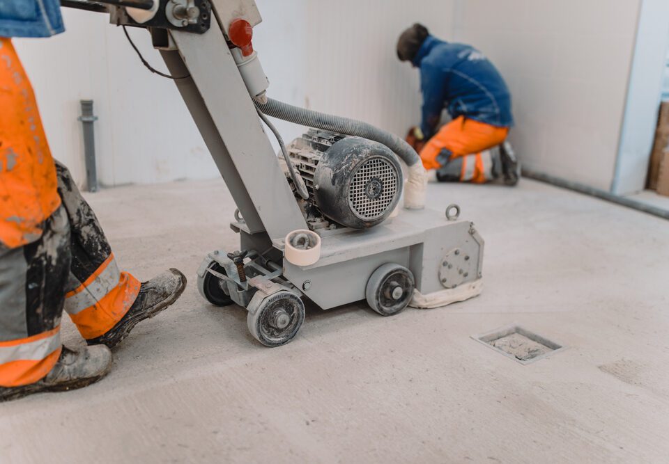 Workers grind the concrete floor at the construction site.