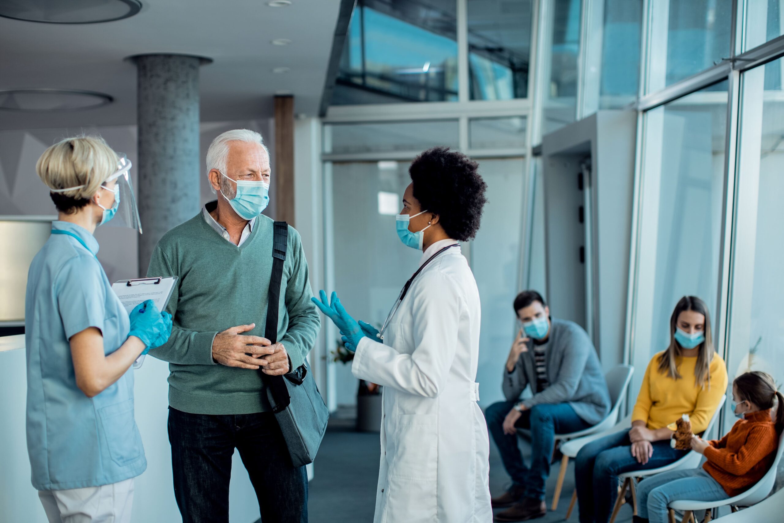 senior man with protective face mask talking doctors hospital hallway (1)